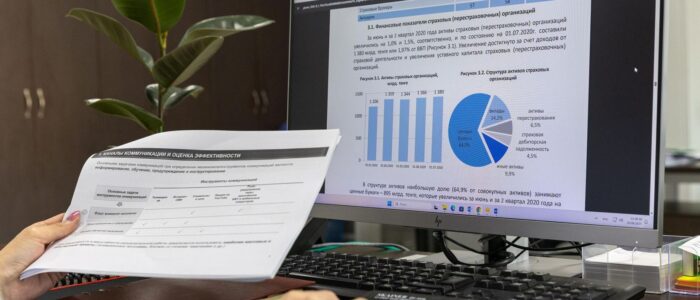 En person som granskar tryckta dokument framför en datorskärm.
